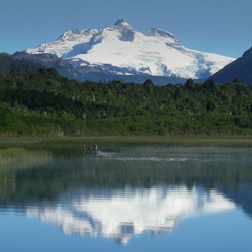 Expert fly fishing guide casting on the pristine waters of Hess Lake, Bariloche, Patagonia, Argentina. Experience world-class day fishing trips with a top-rated outfitter.