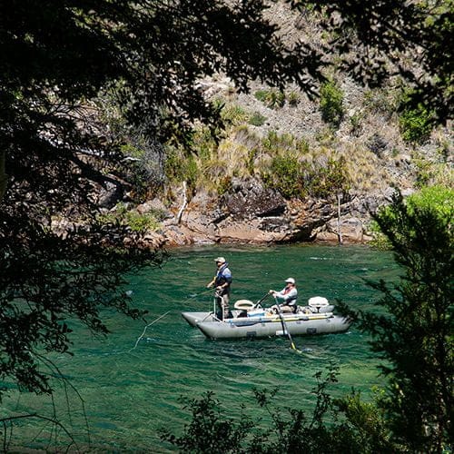 Guided fly fishing expedition on the Manso River, Bariloche, Patagonia, Argentina, featuring anglers in an outfitter boat surrounded by lush scenery
