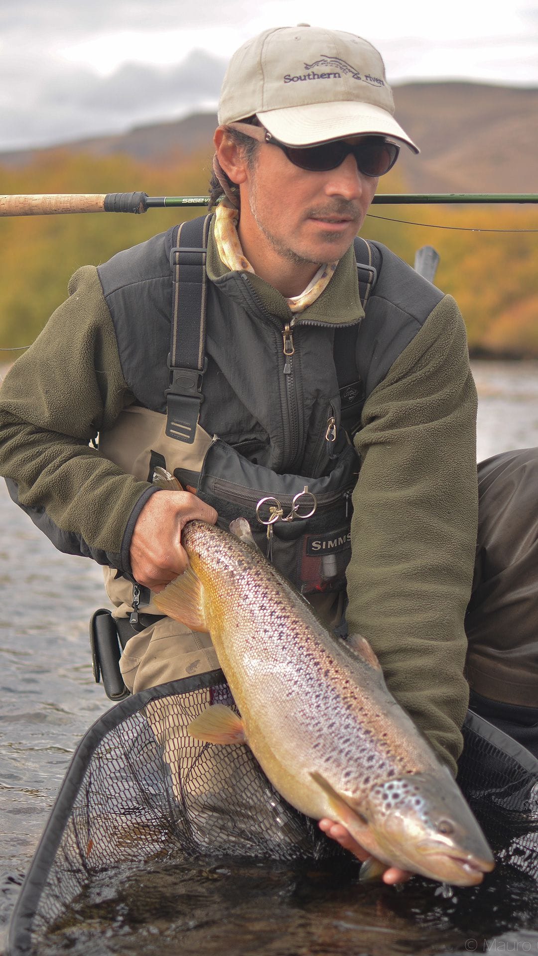 Lucas Valenti, professional fly fishing guide, holding a large brown trout caught during a fishing trip to Limay river in Bariloche, Patagonia, Argentina