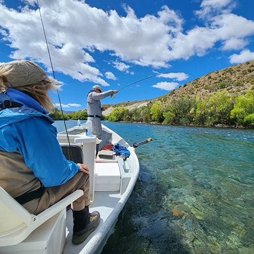 Fly fishing guide service on the Limay River in Bariloche, Patagonia, Argentina, with anglers on a boat enjoying guided trout fishing trips